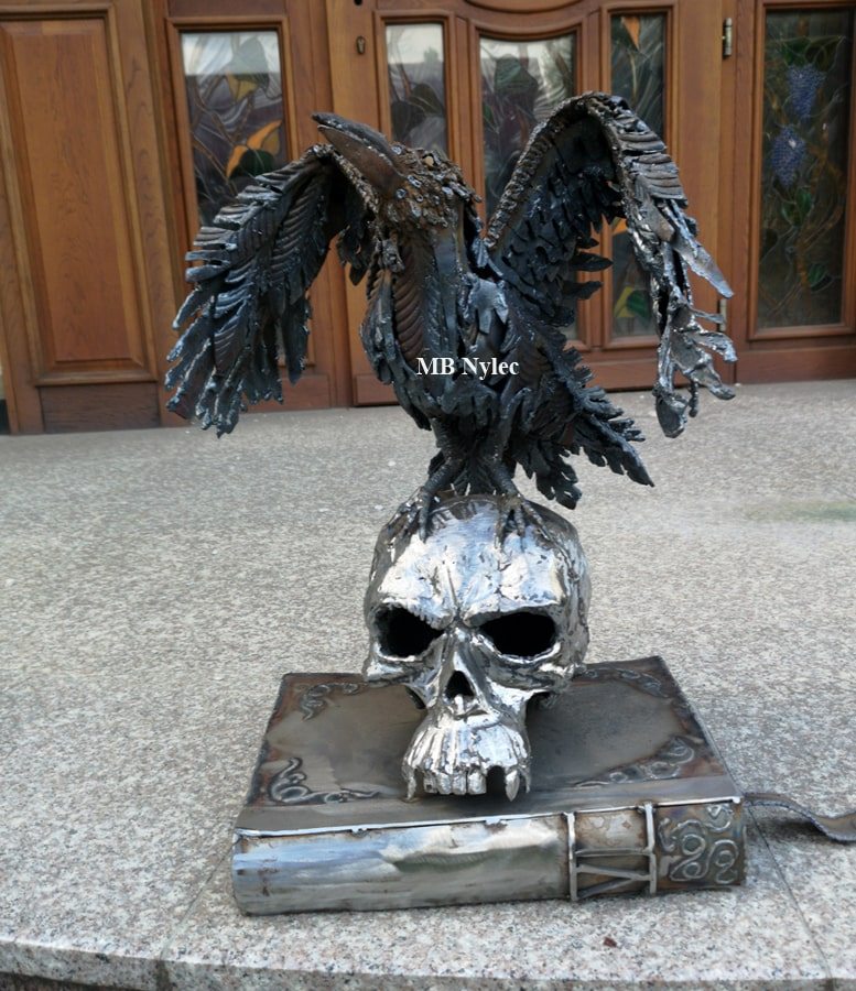 Raven, skull and book metal sculpture in front of a door