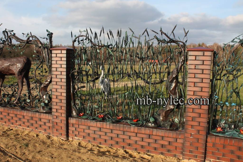 Forged reed fence BM49 with a heron on a brick wall beside a field