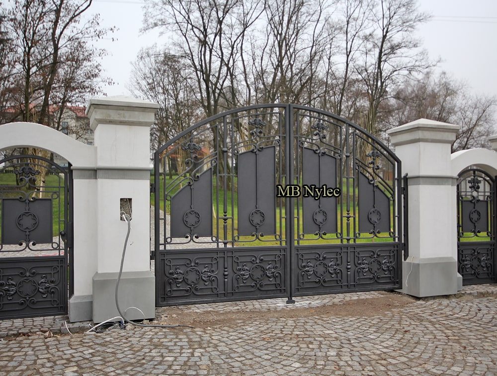 Residence gate BP52 seen at an angle beside a matching wicket set in a white wall