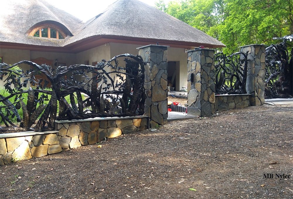 Sculpted 3D steel fence on a stone base in woodland