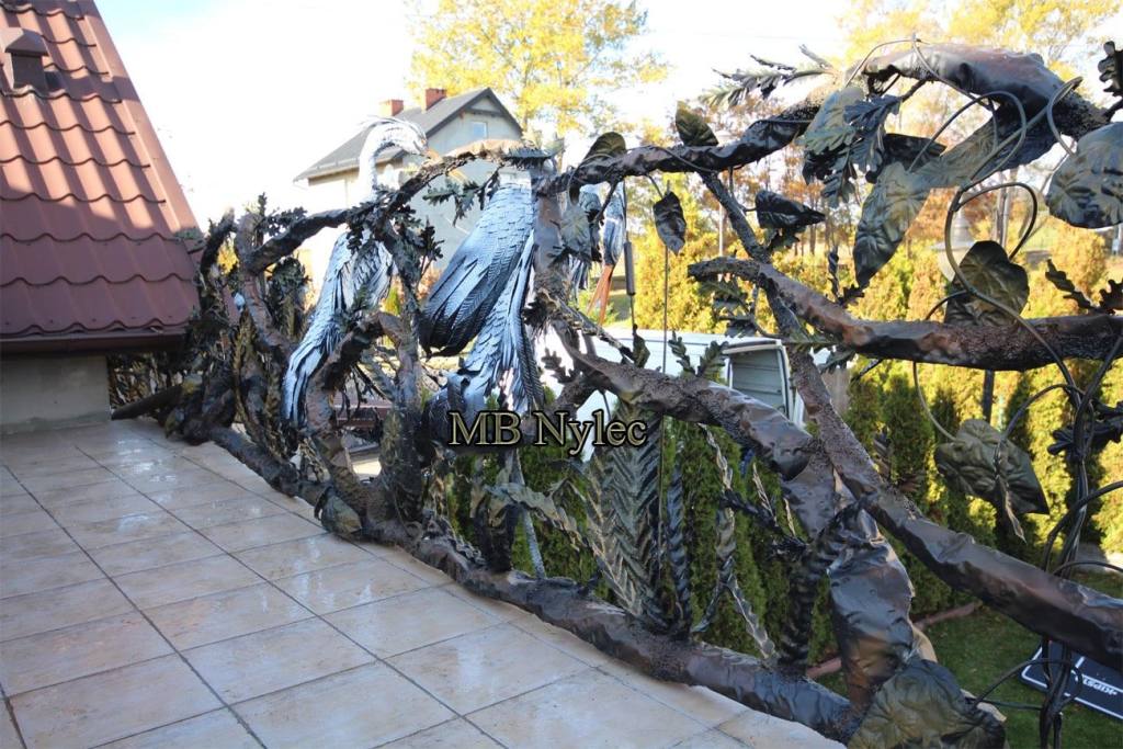 Long sculpted terrace railing of forged branches with large steel birds