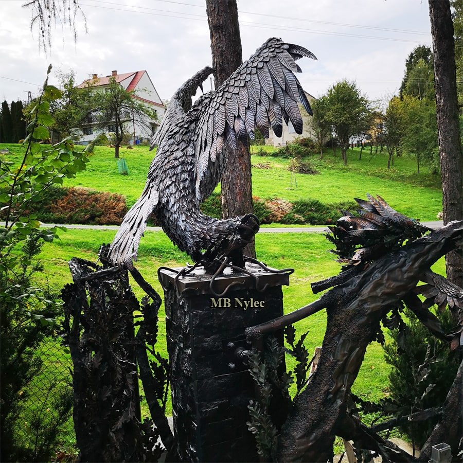 Side view of the steel eagle owl Z120 lifting its wings above a forged pillar cap