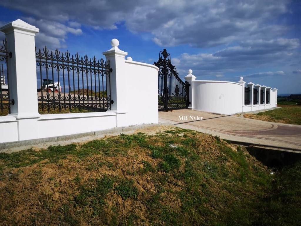 Steel entrance gate with fence panels on a white wall