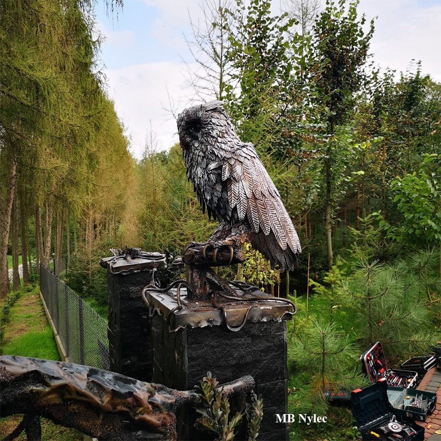 Steel owl figure standing on a gate pillar