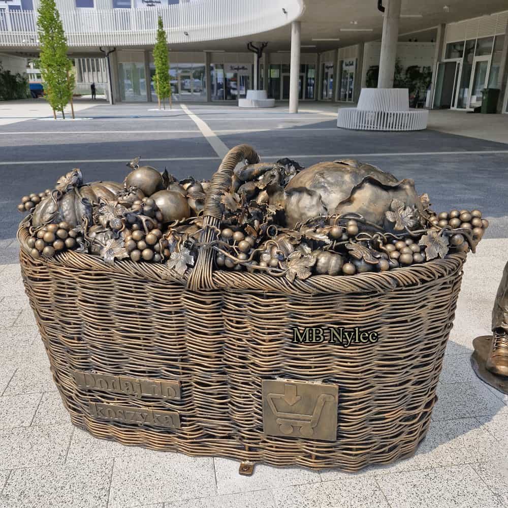 Large steel sculpture of a wicker basket full of fruit and vegetables