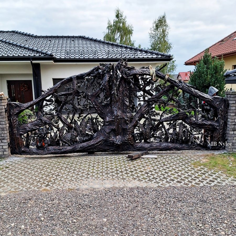 Steel tree sculpture gate between brick pillars