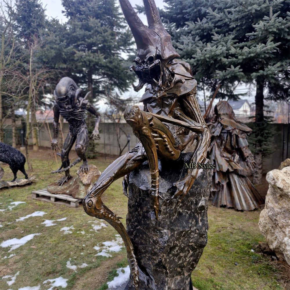 Stone and metal demon sculpture standing in a sculpture garden