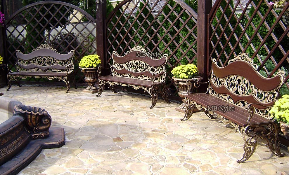 Three palace-style forged benches in a paved courtyard with trellis arches