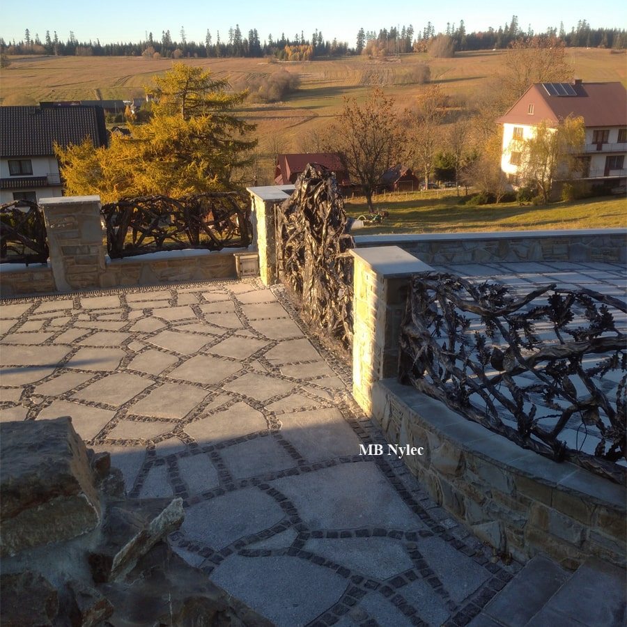 Steel fence panels shaped like branches on a stone wall