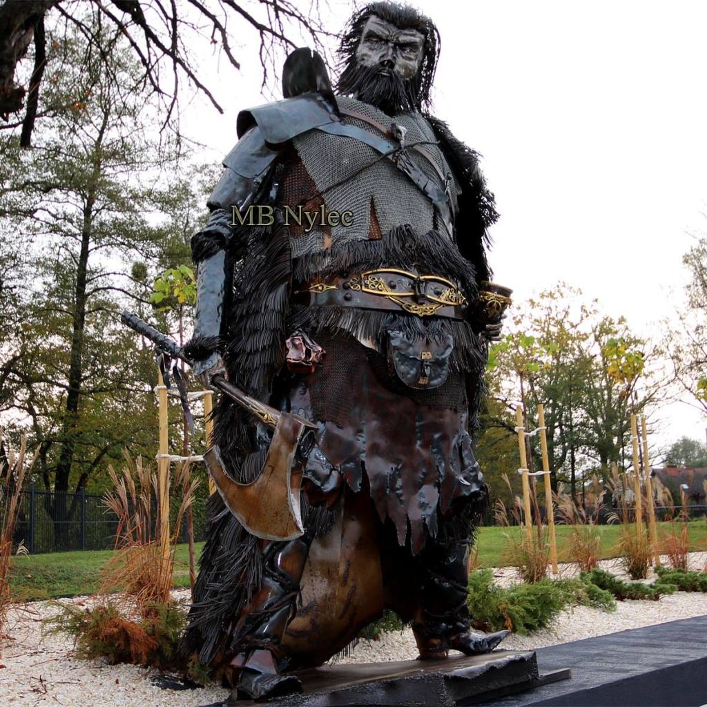 Steel Viking sculpture Z88 with an axe and fur cloak standing in a garden