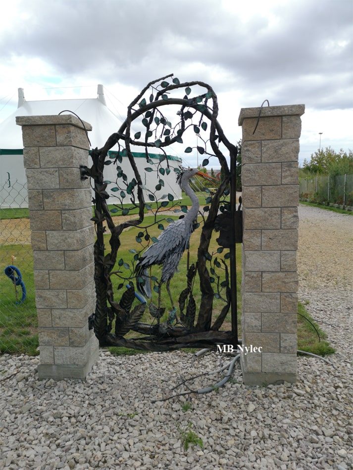 Wicket gate with a metal bird sculpture and forged leaves